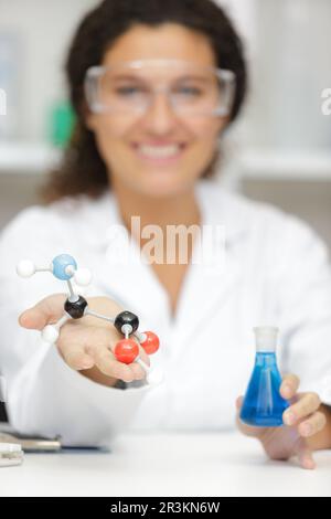 Weibliche Wissenschaftlerin mit Molekülmodell und Glaskolben Stockfoto