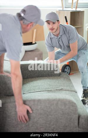 Zwei Umzugsleute, die das Sofa tragen Stockfoto