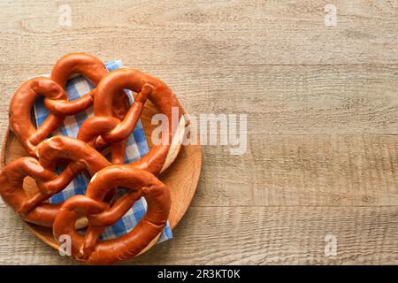 Oktoberfest-Konzeptkarte. Traditionelle bayerische Brezeln mit Bierfläschchen auf rustikalem Holzhintergrund. Perfekt für das Oktoberfest. Oktoberfest foo Stockfoto