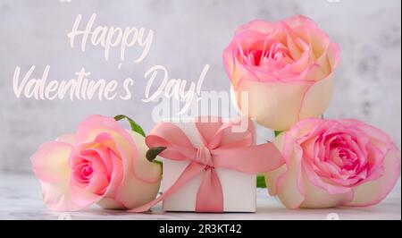 Geschenkbox mit Schleife, pinkfarbene Rosen. Grußkarte. Geschenk für die Frühlingsferien. Text Happy VALENTINES Day. Poster Bann Stockfoto