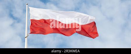 Die Flagge Polens winkt vor dem wunderschönen blauen Himmel. Polnische Flagge Weiß und Rot flattern am blauen Himmel. Nationalflagge von Polan Stockfoto