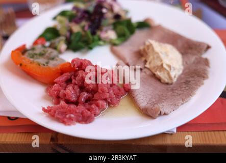 Eine köstliche Vorspeise aus Piedmont. Steak Tartare, Carpaccio, gefüllte Paprika und Salat Stockfoto