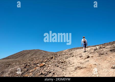 Eine Wanderin erklingt die gut abgenutzten unteren Hänge eines erloschenen Vulkans in Playa Blanca, Lanzarote. Bekannt als der rote Berg oder Montana Roja. Stockfoto