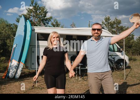 Ein glückliches Paar ruht sich in der Natur neben seinem Wohnmobil aus. Stockfoto