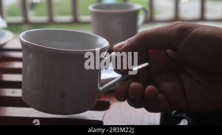 Nahaufnahme eines Mannes, der einen Becher hielt und Kaffee auf dem Balkon trank. Stockfoto
