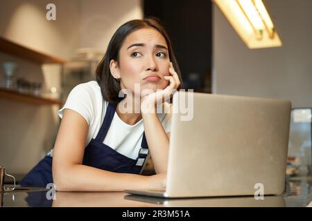 Porträt einer koreanischen Frau, Barista im Café, sah traurig aus und runzelte die Stirn, grimmige Enttäuschung während der Arbeit im Café, Lean Stockfoto