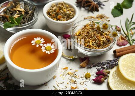 Frisch gebrühter Tee und trockene Blätter auf einem hellen Tisch Stockfoto