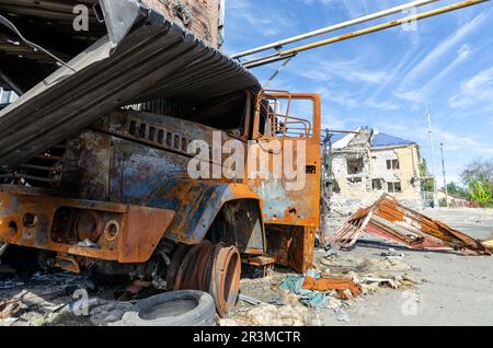 Ein verbranntes Militärauto auf der Straße der zerstörten Stadt Stockfoto