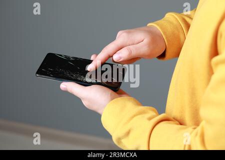 Mann hält beschädigtes Smartphone auf hellgrauem Hintergrund, Nahaufnahme. Gerät wird repariert Stockfoto