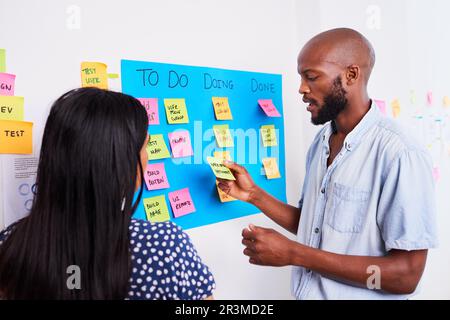 Zwei Entwickler verschieben Tickets während der Sprintplanung auf dem Scrum Board Stockfoto