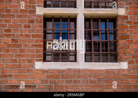 Hostel-Inschrift in Neonlichtern bei Nacht. Elektrisches Nachtleben-Konzept. Moderne fluoreszierende Lebensstil-Lumineszenz. Stockfoto