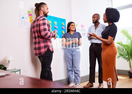 Das Scrum-Team nimmt täglich an Stand-up-Aktivitäten auf KANBAN-Boards und Entwicklern von Apps für Mobilgeräte Teil Stockfoto