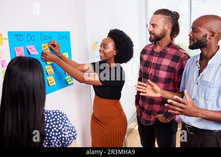 Das Scrum-Team nimmt täglich an Stand-up-Aktivitäten auf KANBAN-Boards und Entwicklern von Apps für Mobilgeräte Teil Stockfoto