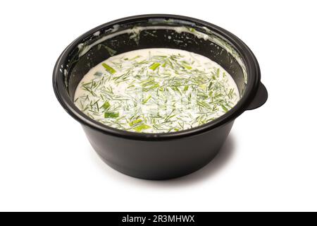 Traditionelle Sommersuppe Okroshka in einer schwarzen Kunststoffbox isoliert auf weißem Hintergrund. Stockfoto