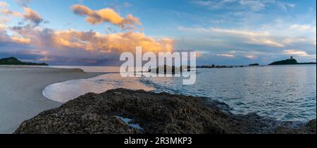 Panoramablick auf den farbenfrohen Sonnenuntergang am Nora Beach auf Sardinien mit dem Coltellazzo Tower im Hintergrund Stockfoto