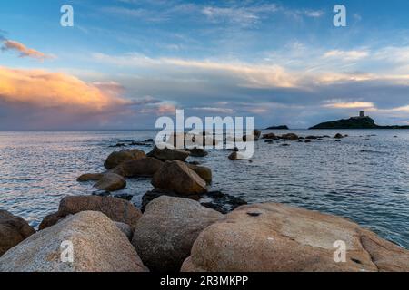 Landschaftsblick auf einen farbenfrohen Sonnenuntergang am Nora Beach in Sardinien mit dem Coltellazzo Tower im Hintergrund Stockfoto