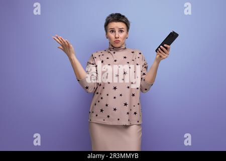 Aufgeregte junge, grauhaarige europäische Frau mit kurzem Haarschnitt, die ein Smartphone in der Hand hält Stockfoto