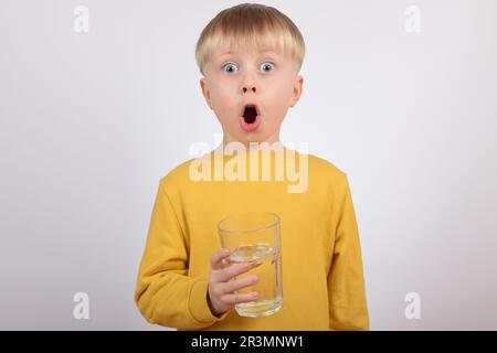 Junger Junge, der klares Wasser aus Glas trinkt Stockfoto