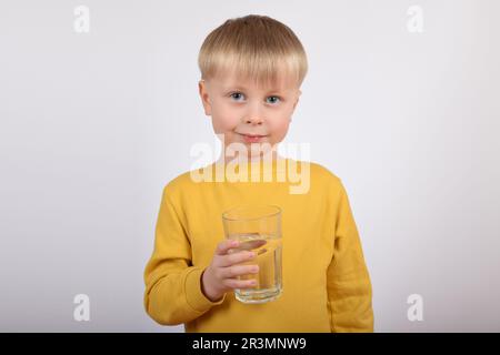 Junger Junge, der klares Wasser aus Glas trinkt Stockfoto