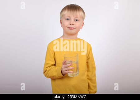 Junger Junge, der klares Wasser aus Glas trinkt Stockfoto