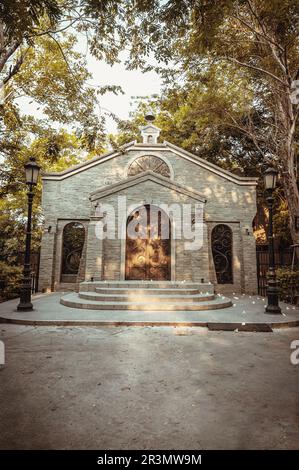 NakhonSawan, Thailand - 23. April 2023 - Antike eiserne Bogentür an einer Ziegelsteinwand in einem historischen Backsteingebäude, umgeben von Straßenlaternen Stockfoto