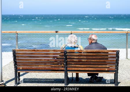 Yport, der Kieselsteinstrand, das kleine Boot und die Klippen vor der Nordsee - ein paar alte Leute sitzen auf einer Bank | Yport ein Quelques Kilometer Stockfoto