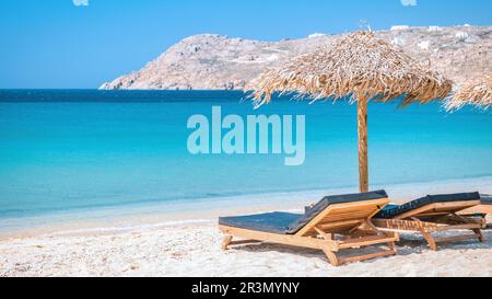 Mykonos Strand im Sommer mit Sonnenschirm und luxuriösen Liegestühlen, blauer Ozean Griechenland Stockfoto