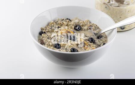 Hafer über Nacht mit Chiasamen, Rosinen, Blaubeeren, getrockneten Pfirsichen, Zimt und Rosinen - köstliches, gesundes Frühstück Stockfoto