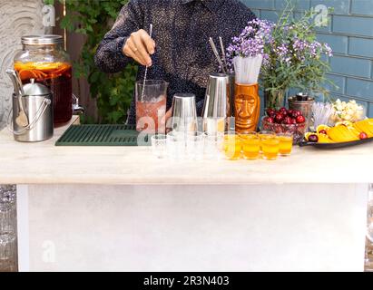 Gläser Cocktails an der Bar. Der Barkeeper schenkt ein Glas Sekt mit rotem Alkohol ein. Stockfoto