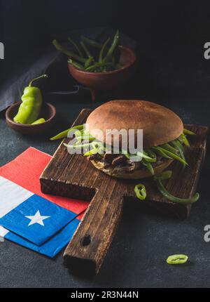 Chilenischer lateinamerikanischer Sandwich-Burger Chacarero mit hochwertigen Rinderschnitten und grünen Bohnen auf schwarzem Hintergrund. Stockfoto