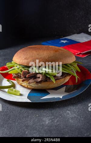 Chilenischer lateinamerikanischer Sandwich-Burger Chacarero mit hochwertigen Rinderschnitten und grünen Bohnen auf schwarzem Hintergrund. Stockfoto