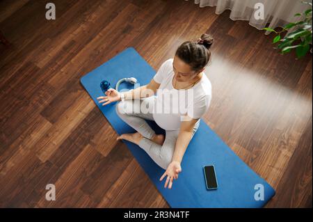 Draufsicht einer schwangeren Frau, die zu Hause Yoga macht und auf die Geburt ihres Babys wartet. Gesundheit und Wellness Stockfoto
