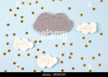 Gestricktes Spielzeug Wolken und gelbe Sterne auf blauem Hintergrund. Babysachen und Accessoires. Draufsicht, flach liegend Stockfoto