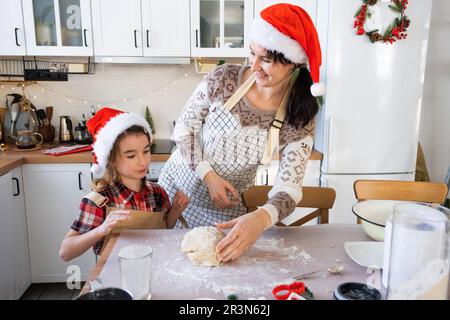 Mom und Tochter in der weißen Küche bereiten Kekse für Weihnachten und Neujahr zu. Familientag, Vorbereitung auf den Urlaub, Stockfoto