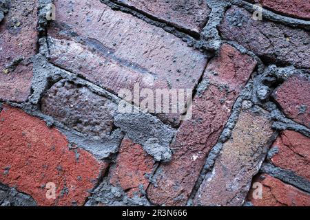 Eine moderne Mauer. Dunkelrote Ziegel sind kunstvoll verlegt und mit dunkelgrauem Zement verfugt. Stockfoto