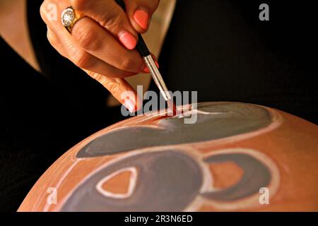 Künstlerin, die den Bauch einer schwangeren jungen Frau malt Mit Körperfarben und Pinsel Stockfoto