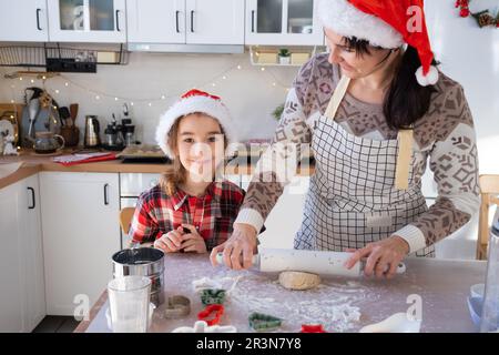 Mom und Tochter in der weißen Küche bereiten Kekse für Weihnachten und Neujahr zu. Familientag, Vorbereitung auf den Urlaub, Stockfoto