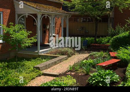 Ein Gartenbereich vor einem kleinen Geschäft ist eine erholsame Oase vom modernen Leben im historischen Roscoe Village am Rande von Coshocton, Ohio. Stockfoto