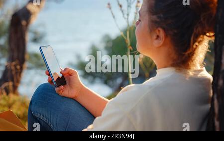 Reise- und Lifestyle-Konzept. Glückliche lächelnde Frau beim Wandern in den Bergen, Fethie, Türkei. Junger Hiker mit Smartphone, digitale Kommunikation. T Stockfoto