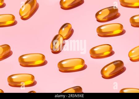 Uber die Zusammensetzung orangefarbener Vitaminpillen auf pinkfarbenem Hintergrund im Lichtstudio Stockfoto