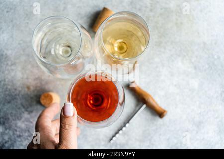 Draufsicht einer nicht wiedererkennbaren Person mit drei Hauptsorten georgischer Trockenweine - weiß, rot und orange auf einem Betongrauen Tisch mit einem Korkenzieher an Stockfoto