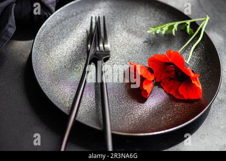 Sommertisch mit roten Mohnblumen auf schwarzem Teller auf Betonhintergrund Stockfoto