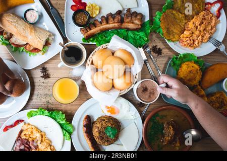 Blick von oben auf die unbekannte Frau, die Kakao trinkt und verschiedene köstliche lateinamerikanische Gerichte isst, während sie bei Tageslicht im Restaurant zu Mittag isst Stockfoto