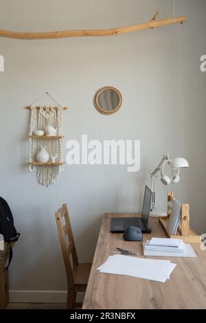 Minimalistisches Studentenzimmer und Holztisch mit Stuhl und Laptop in der Nähe eines Fensters in einer modernen Wohnung Stockfoto
