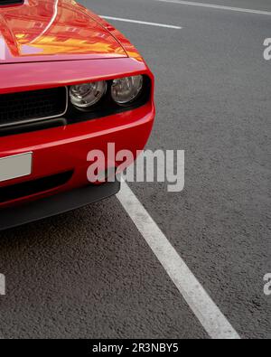 Luxuriöser roter Sportwagen mit glänzenden Scheinwerfern auf Asphaltstraße in der Stadt Stockfoto