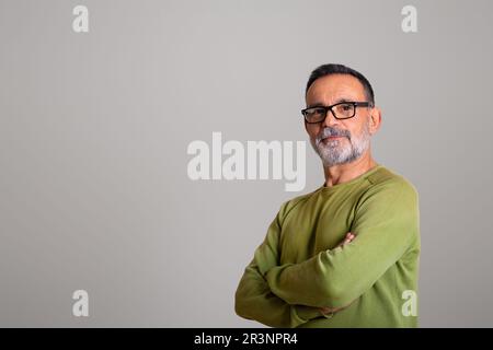 Ein ernster selbstbewusster muskulärer Kaukasier im Alter in Brille mit Bart und gekreuzten Armen Stockfoto