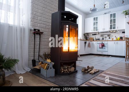 Schwarzer Herd, Kamin im Innern des Hauses im Loftstil. Alternative umweltfreundliche Heizung, warmes, gemütliches Zimmer zu Hause, brennendes Woo Stockfoto