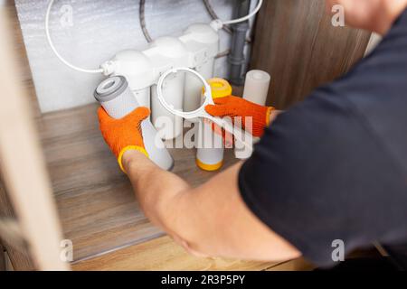 Der Installateur installiert oder wechselt den Wasserfilter. Ersatz-Aqua-Filter Stockfoto