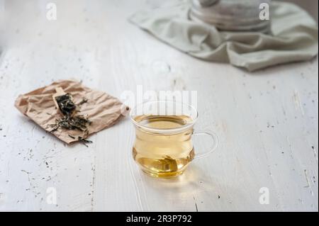 Frisch zubereiteter weißer Tee auf einem verwitterten Holzbrett mit klassischer Teekanne im Hintergrund Stockfoto