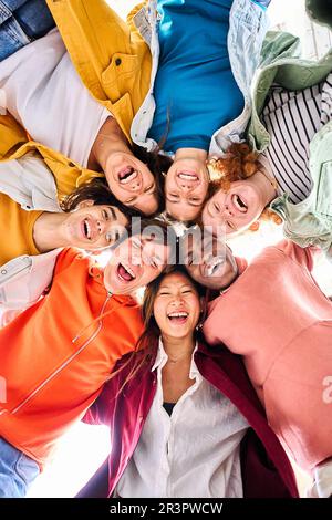 Vertikale, große, multiethnische Gruppe von lächelnden jungen Menschen, die sich umarmen und in die Kamera schauen. Stockfoto